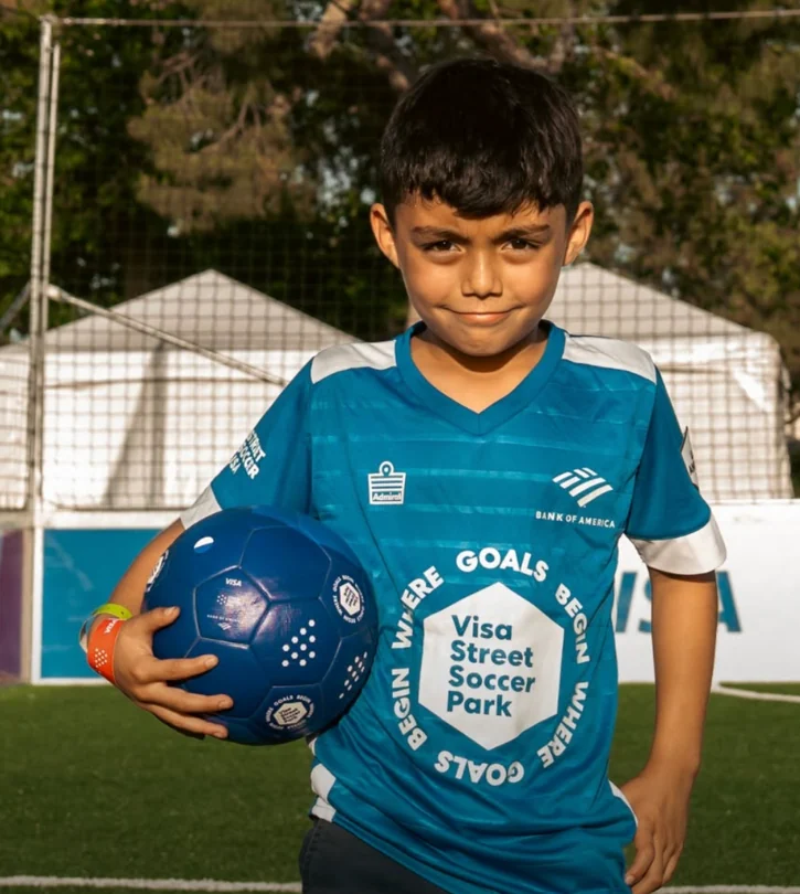 A young Street Soccer USA player holding a soccer ball